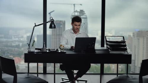 Excited businessman celebrates success reading good news on laptop in modern office