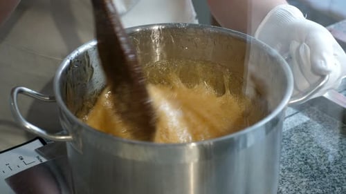 Closeup Liquid Caramel Slowly Drains From the Saucepan Onto a Baking Sheet