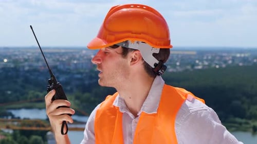 Construction Worker Talking on Walkie Talkie at Building Site