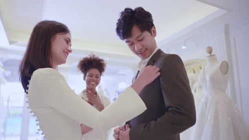 Asian beautiful bride trying on wedding gown with her fiance in studio.