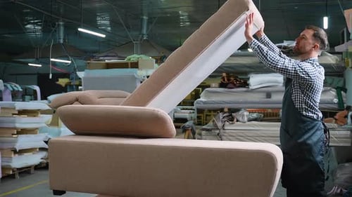 Man Testing Sofa Lift Mechanism in Furniture Workshop
