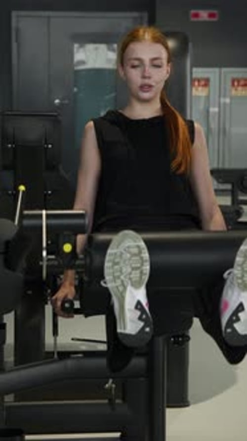 Jovem adorável mulher ruiva sob supervisão de um personal trainer está realizando exercícios em