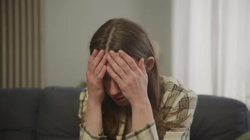 Shocked Woman Holding Head In Hands After Receiving Devastating News Indoors