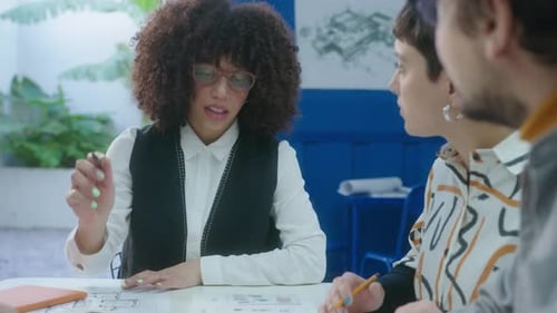 Team Discusses Architectural Blueprints at Office Table