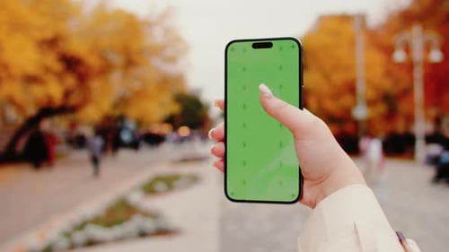 Woman Using Smartphone with Green Screen in Autumn Park