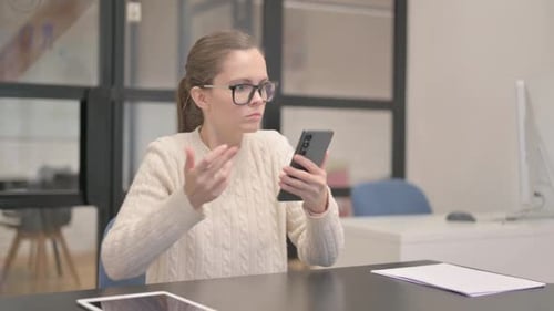 Young Woman Shocked by Loss on Phone in Office