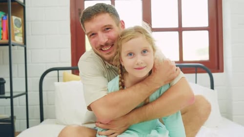 Loving Father Hugs Daughter on Bed at Home