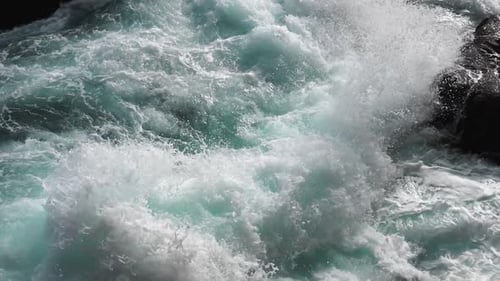 Las olas de color turquesa puro y brillante se rompen en espuma blanca en los acantilados costeros y se bañan