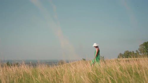 Woman Walking Through Dry Grass in Sunny Countryside Landscape