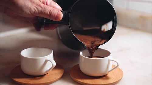 Dark Liquid Pouring Into a White Coffee Cup