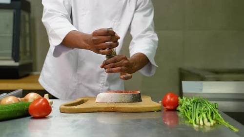Chef Prepares Salmon with Herbs in Restaurant Kitchen