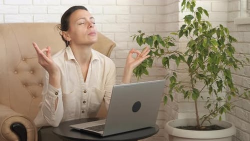 Woman Meditating at Home Next to Laptop