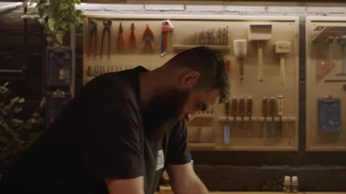 Focused woodworker crafting furniture in workshop surrounded by tools