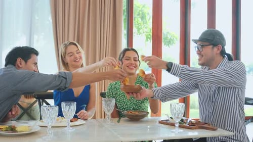 Group of diverse friend talking and eating food together in restaurant.