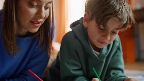 Woman and Boy Drawing Together Indoors with Colored Pencils