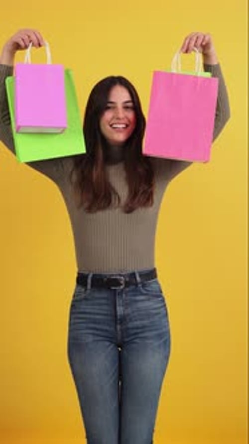 Woman Holding Shopping Bags Smiling on Yellow Background