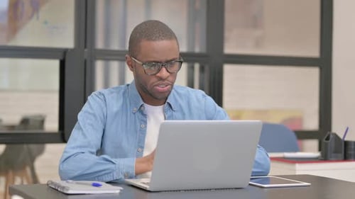 African Businessman Chatting Online on Laptop while Sitting in Office