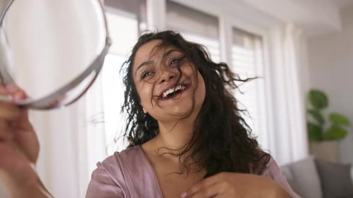 Schöne junge übergewichtige Frau drinnen zu Hause, schaut in den Spiegel