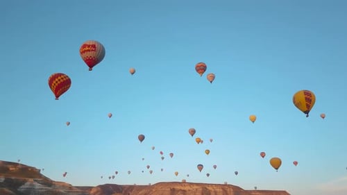 Montgolfières survolant un ciel bleu vif, au-dessus d'un paysage de montagne, Cappadoce, Turquie