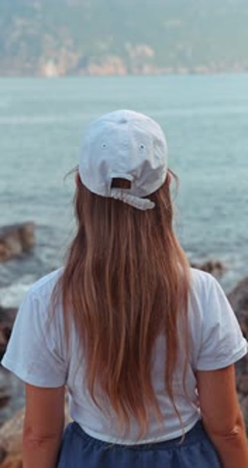 Woman with Long Hair Looking at Sea on Coastal Landscape