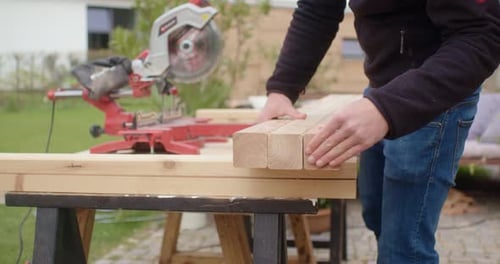 Carpenter Prepares Wood for Miter Saw Outdoors