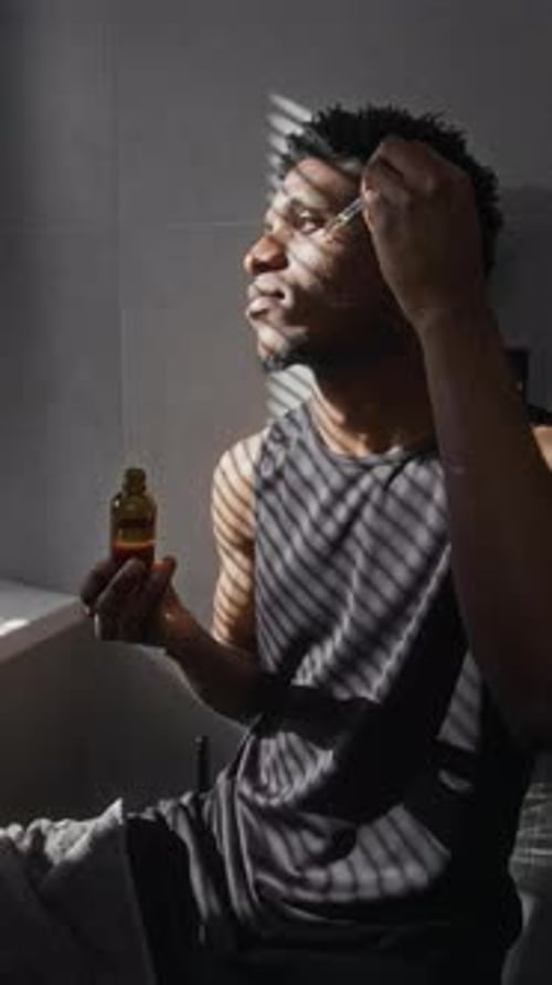 Man Applying Facial Serum in a Bathroom