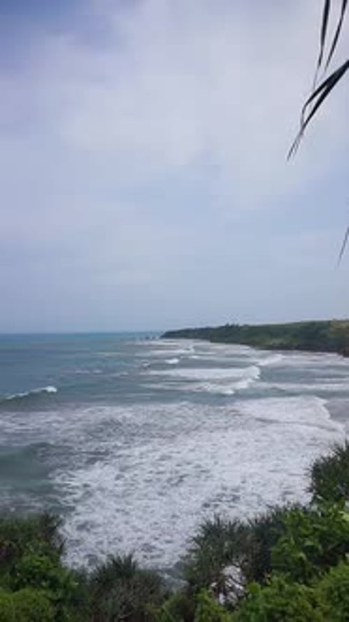 beautiful vertical video stretch of beach with blue sea water with big waves during the day
