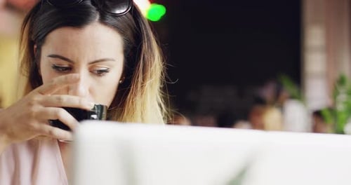 4k video footage of an attractive young woman sitting alone in a cafe and using her laptop