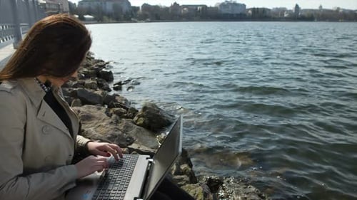 Businesswoman with Laptop Sitting on a Beach in the Sea Coast