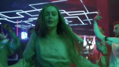 Group Of Young Friends Dances Together In Neon Light Of Night Club. Energetic Playful Moves In Di...