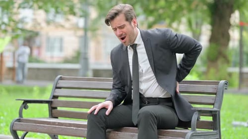 Man Experiencing Back Pain While Sitting on Bench