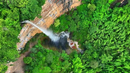 Aerial view: Majestic waterfall cascades from cliff.