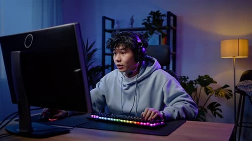 Teen Gamer Celebrates Victory in Dimly Lit Room