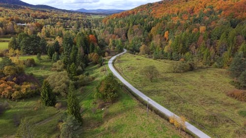 Aerial View Of Winding Countryside Road Through Fall Forest Hills