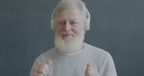 Senior Man Enjoys Music With Headphones On