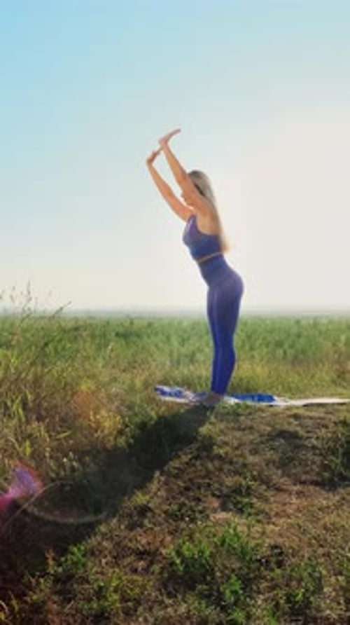 Frau praktiziert Yoga im Freien in einer ruhigen Landschaft mit leuchtendem Grün und Sonnenlicht