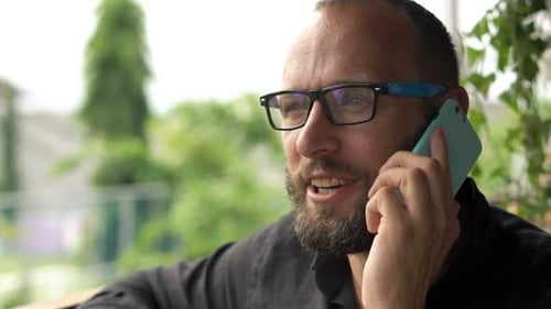 Man Talking On Cellphone And Drinking Coffee Sitting In Cafe