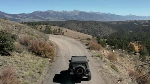 fly over shot with drone of off roading in the mountains with beautiful lake