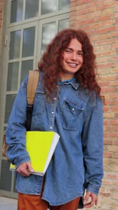 Portrait vertical d'un étudiant non binaire heureux à l'extérieur souriant avec confiance dans un cadre décontracté avec