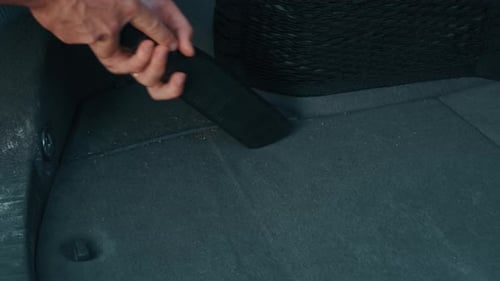 Person vacuuming car trunk floor with vacuum attachment