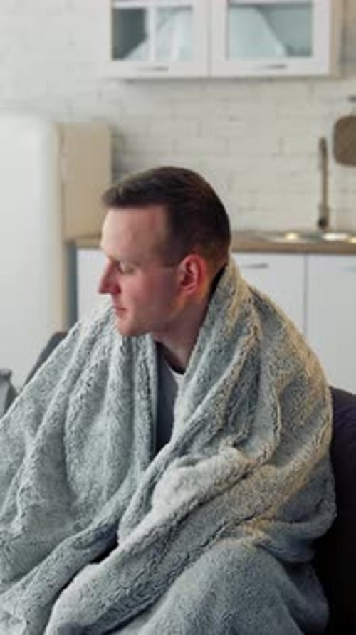Man Wrapped in Blanket Resting on Couch
