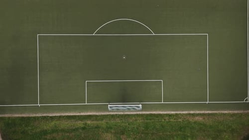 Top Down View of a football goal on an empty, green football field in the middle of the forest, Dron