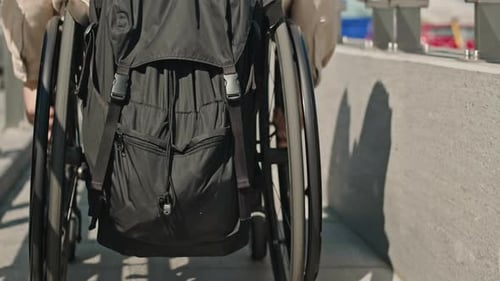 Wheelchaired Man Riding along Bridge Back View