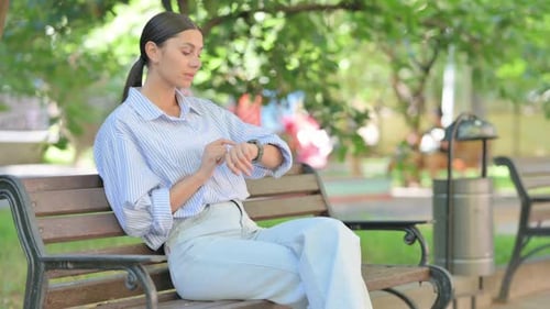 Woman Using Smart Watch on Park Bench