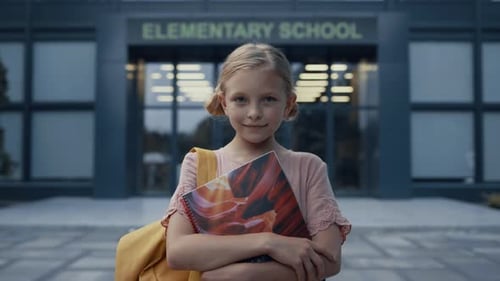 Little Elementary Age Girl Holding Books Posing at Campus Door Close Up