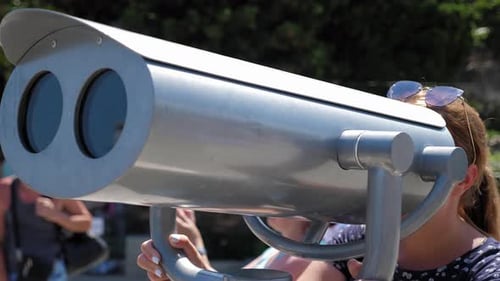 A Woman Looks Through Stationary Binoculars on an Observation Deck By the Sea