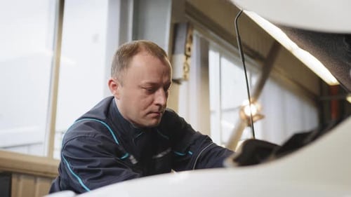 Auto Mechanic Inspecting Car Engine in Garage