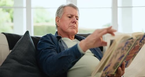 Mature Adult Reading a Book on the Sofa
