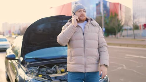 Man Talking on Phone Next to Car on Street