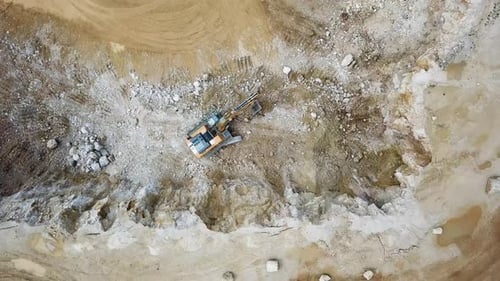 An excavator mines material and loads a truck.